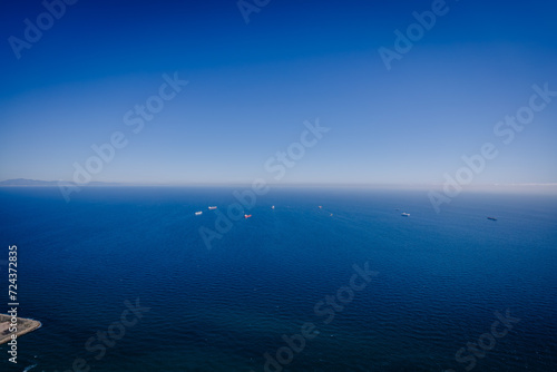 Gibraltar, Britain - January 24, 2024 - clear blue sea with several ships and a distant mountain range under a bright blue sky.