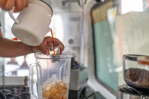 Barista pouring coffee to a blender to prepare iced coffee photo