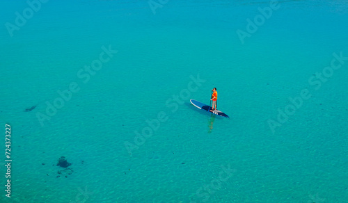 Canvas Print Happy Asian young man  standing on a sup Surfing balancing on supboard paddling
