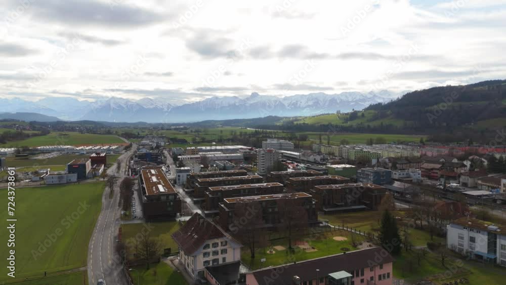 Swiss town with quaint houses against a backdrop of majestic snow-capped Alps, cloudy skies, aerial view Swiss town with quaint houses against a backdrop of majestic snow-capped Alps, cloudy skies, aerial view