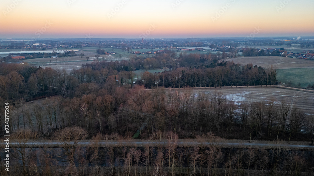 This image portrays the quiet beauty of an early morning in the countryside, with a soft dawn light gently illuminating the frost-kissed fields. A thin mist hovers over the horizon, softening the This image portrays the quiet beauty of an early morning in the countryside, with a soft dawn light gently illuminating the frost-kissed fields. A thin mist hovers over the horizon, softening the