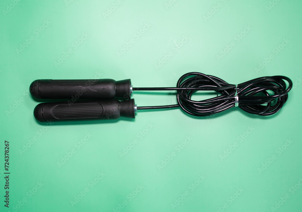 Skipping rope with black handles on the green background. Skipping rope with black handles on the green background.