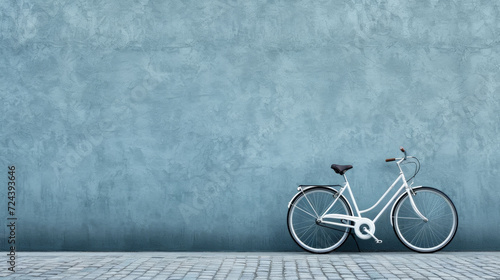 Classic white bicycle leaning on a textured blue wall, symbolizing an eco-friendly mode of transport in a modern city setting. photo