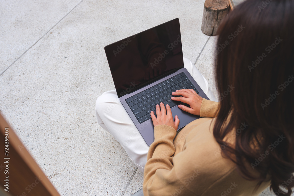 Top view image of a young woman sitting and working on laptop computer Top view image of a young woman sitting and working on laptop computer