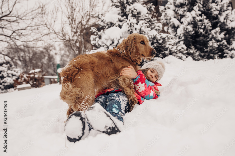 A girl plays in the snow with a dog in winter. Beautiful red dog, beautiful girl.