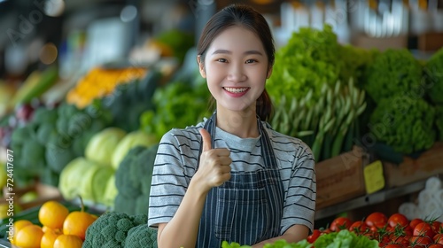 An Asian woman standing and giving the thumbs up in front of the veggie  supermarket shop  space  Generative AI.