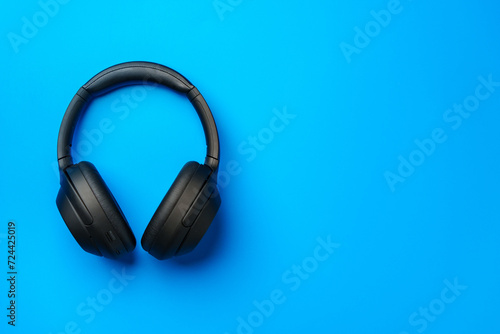 Black headphones on blue background top view