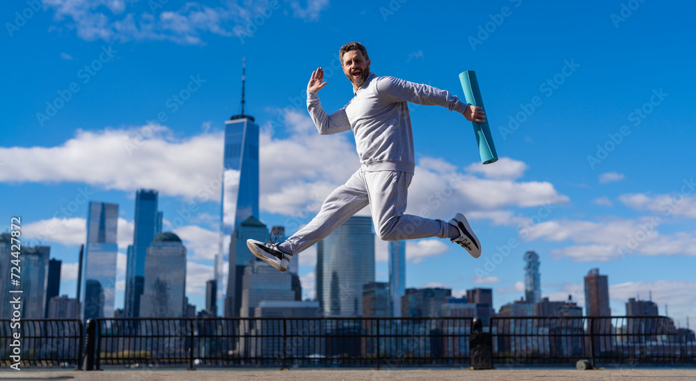 Sport lifestyle. Sportsman running with fitness mat. Sport man training outdoor in New York. Healthy lifestyle with daily fitness. Fitness and sport. Man jumping with energy. Banner