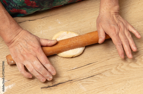 A woman rolls out dough with a rolling pin