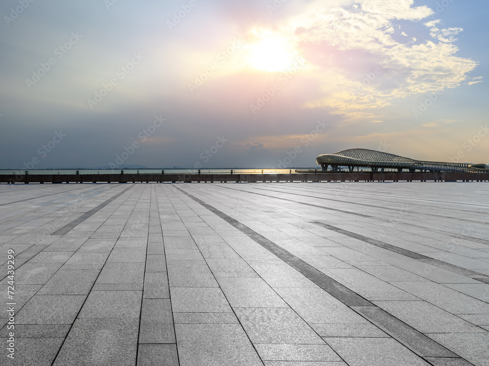 Empty square floor and lake with sky clouds at sunset