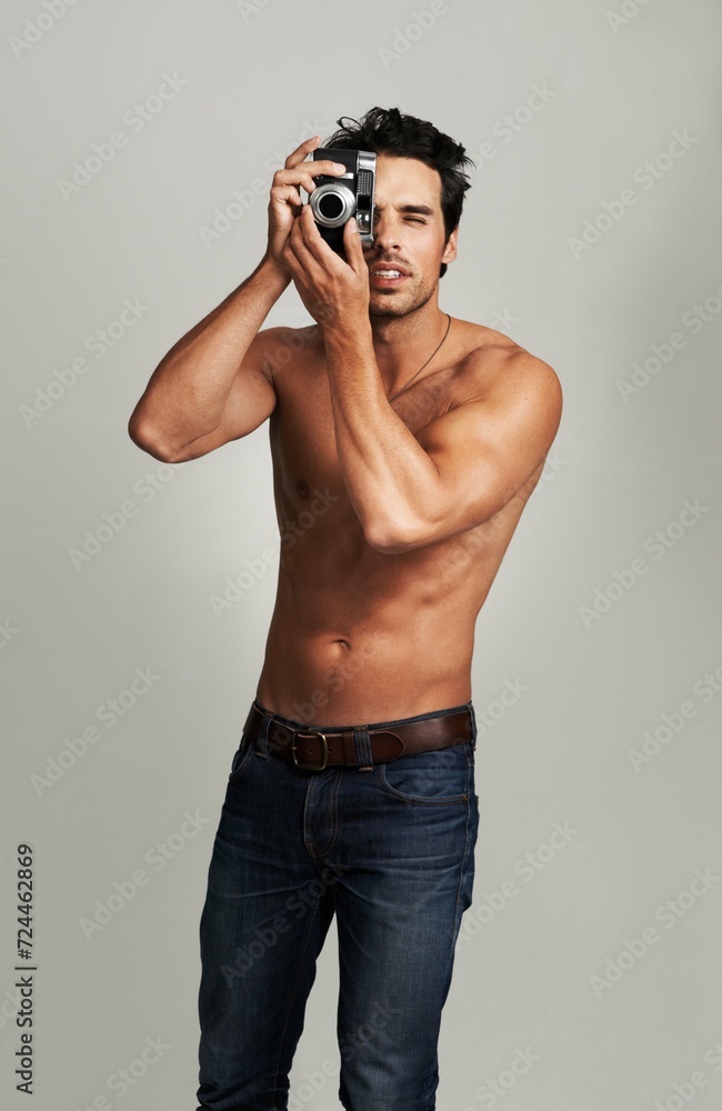 Fototapeta premium Camera, shirtless and young man in a studio with art, creative and photography career. Confused, doubt and attractive male photographer from Canada with dslr equipment isolated by gray background.