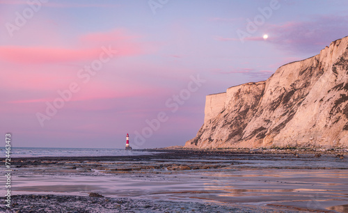 Sunrise and moonset at beachy head lighthouse during low tide east Sussex coast south east England UK