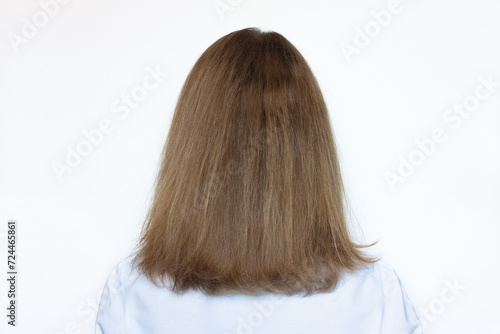 Back view of a woman with damaged dry hair and split ends, isolated on a white background. Concept of health, beauty and keratin treatment for curly or frizzy hair. Model with brown long hair