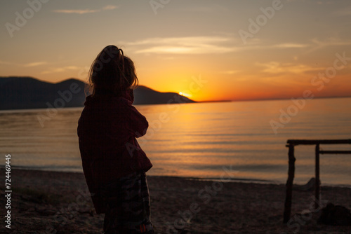 Sneakers on aA girl admiring the sunset. The last rays of the afternoon sun going behind the mountain sandy beach