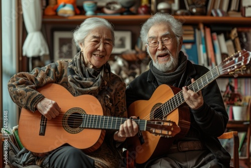 Portrait of an elderly couple enjoying playing the guitar in their own home. They have a smiling and happy face.