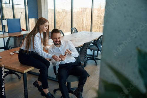 Showing information in the phone. Man and woman employees are working in the office