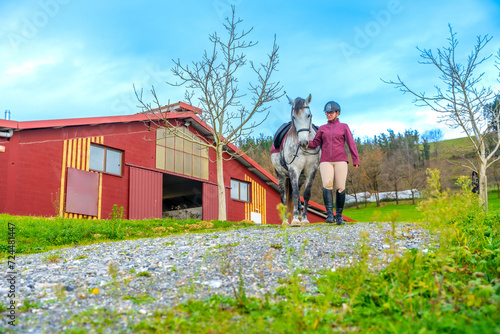 Woman and horse walking outside an equestrian center