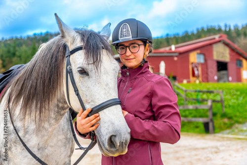 Young girl with her white horse in an equestrian center