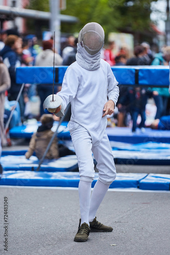 Athletes fencing in a suit uniform with a sword and mask, competition or warm-up. An active Olympic sport. photo