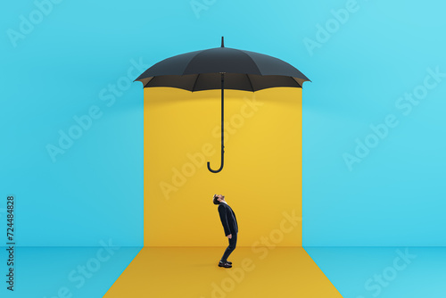 Side view of young male standing under red umbrella on yellow background. Protection and insurance concept. © Who is Danny