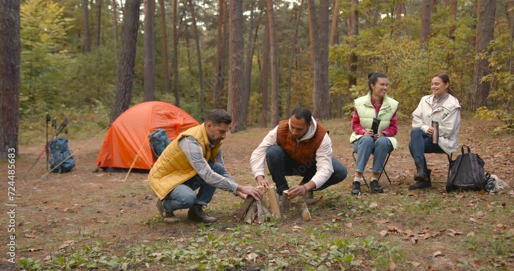 Motivated campers igniting a fire and preparing a barbeque Motivated campers igniting a fire and preparing a barbeque