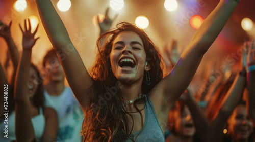 young woman in a party atmosphere, joyfully raising her arms and cheering among a crowd