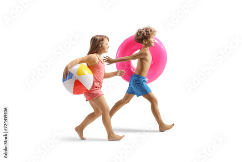 Playful kids in swimwear running and carrying a swimming ring and a ball photo