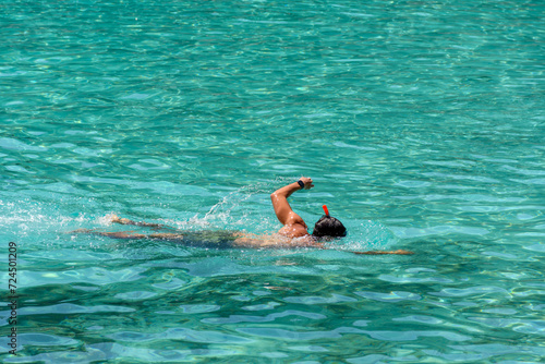 Man swimming and snorkeling with mask in turquoise sea during summer vacation