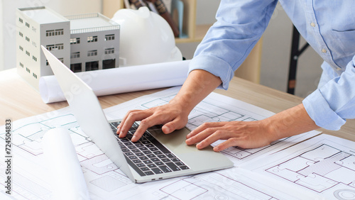 Engineer and construction concept. Engineer technician using laptop to drawing design building project on blueprints and analyzing of project types. Interior design and decoration ideas. Real estate