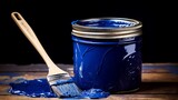 Painter's can of vibrant cobalt blue paint with a bristle brush on top, ready for use on a palette of blue shades
