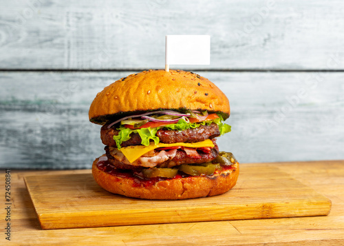 Burger, hamburger, maxi sandwich with two meat cutlets with tomato, cucumber and cheese on a wooden board