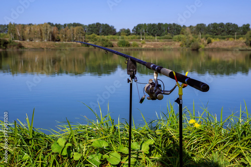 A rod and reel in the background of the lake. Fishing, recreation, hobby.