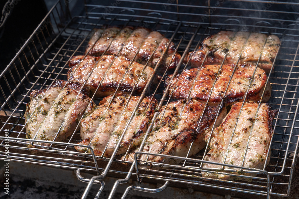 roasted slices of meat on a grill grilled over a fire. Pig meat is cooked on grill grates.