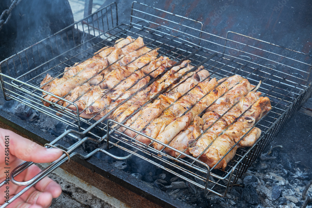roasted slices of meat on a grill grilled over a fire. Chicken meat is cooked on grill grates. Close-up
