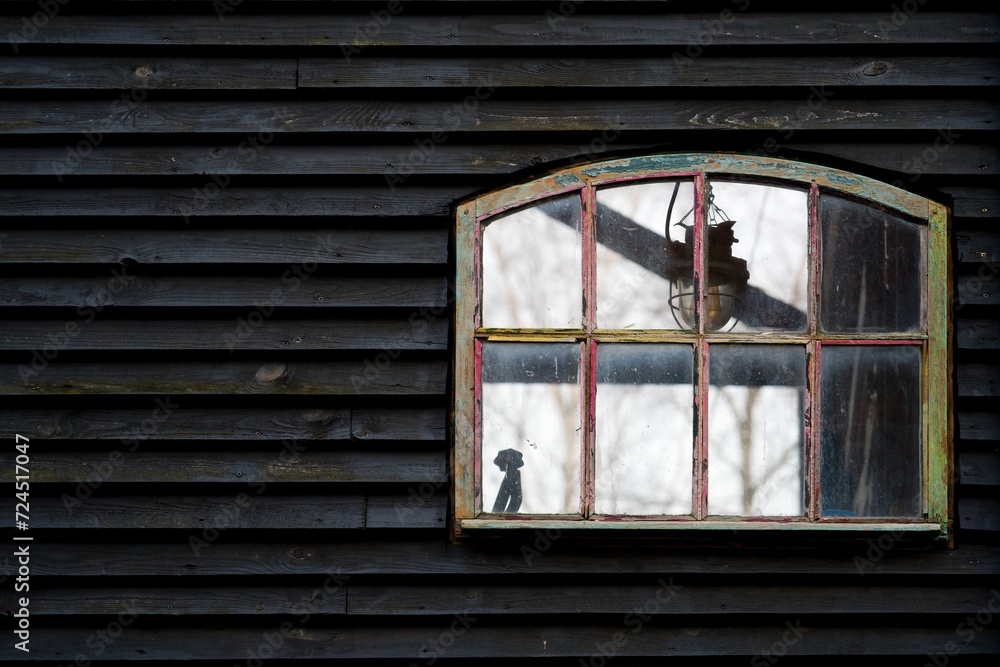 Window in a black wooden wall. Vintage window frame.