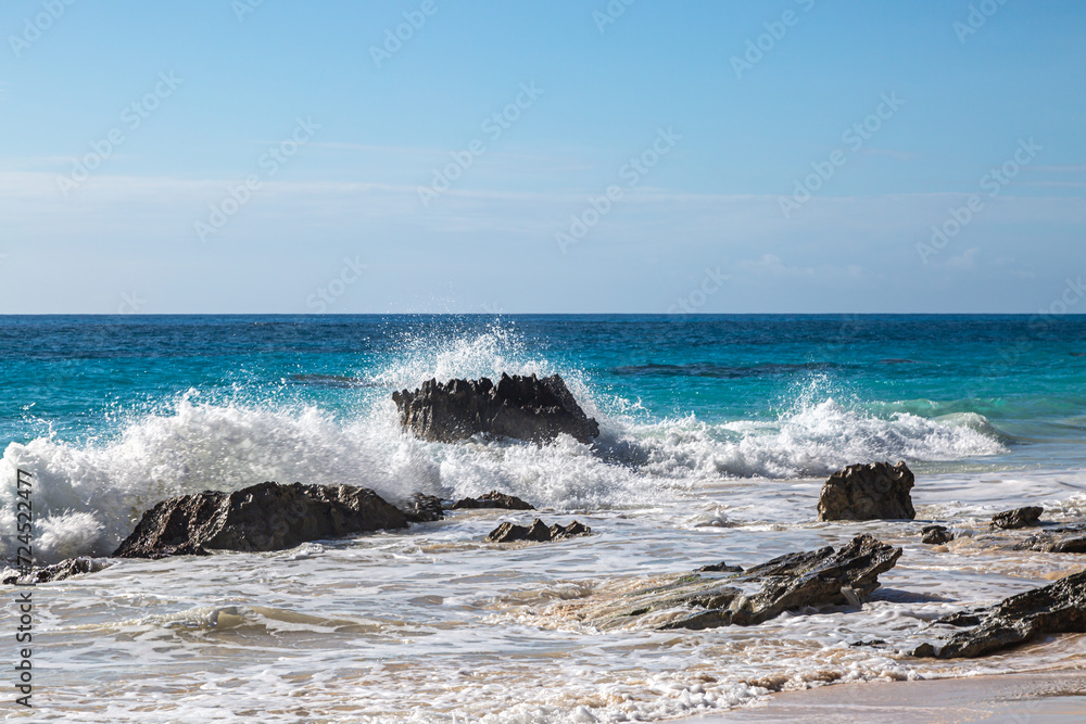 Waves crashing over rocks in the ocean, at Elbow Beach on the island of Bermuda