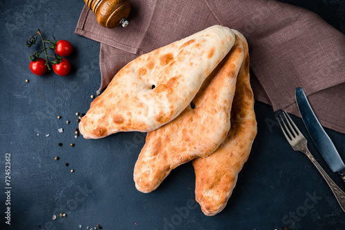 Georgian snack flatbread on a dark background with cherry tomatoes. photo