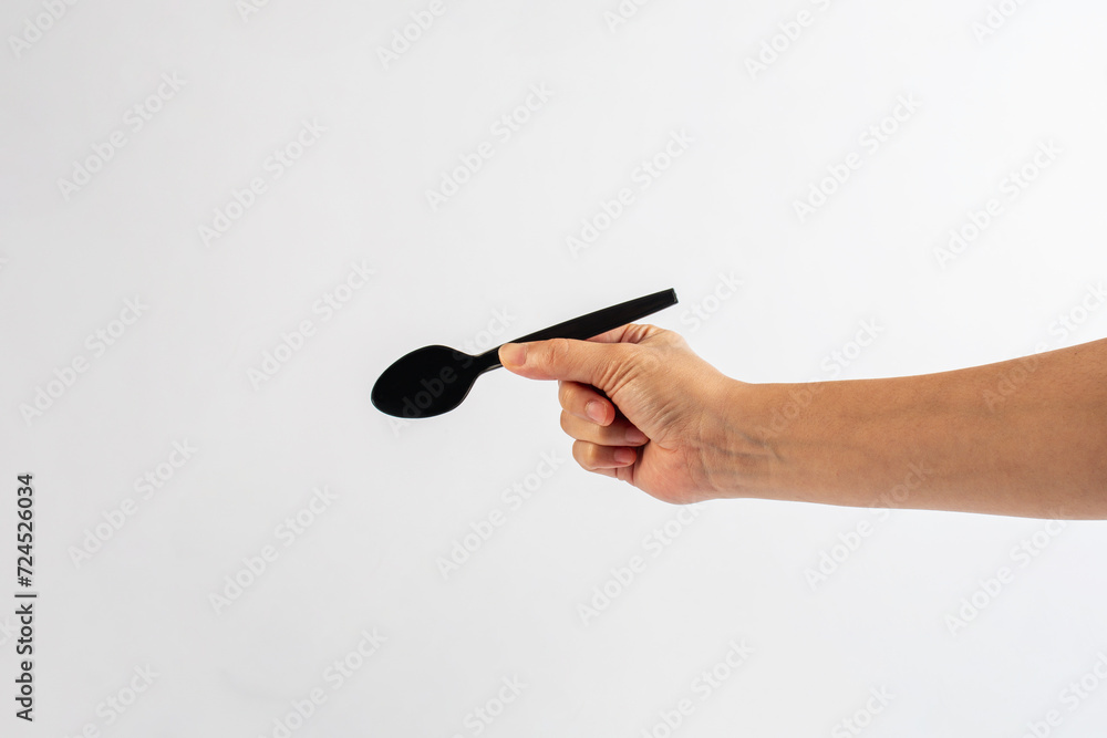 Black plastic spoon in hand on white background Black plastic spoon in hand on white background