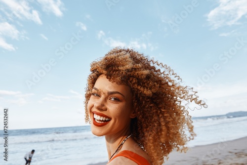 Beach Lifestyle: A Happy Woman with a Smiling Face and Curly Hair, Backpacking for a Vacation Trip, Experiencing Freedom and Joy.