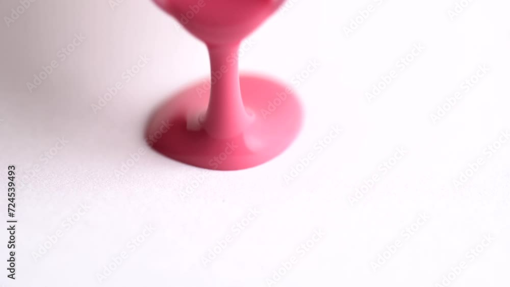 Pink lipgloss pouring on white background.