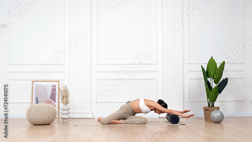 Young athletic female trainer doing fascia exercises on the floor - Caucasian woman using a foam roller - a tool to relieve back tension and relieve muscle pain. photo