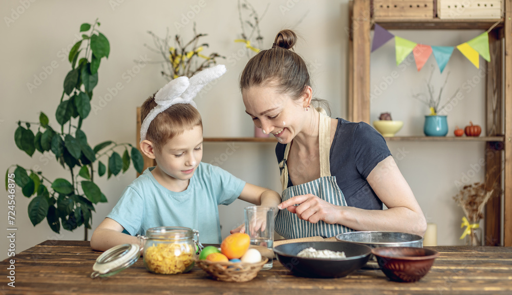 Obraz premium Happy Easter with your family. Mom and son are preparing for spring Easter by cheerfully coloring holiday eggs