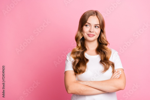 Photo of cheerful woman with wavy hair dressed white t-shirt arms folded look at sale empty space isolated on pink color background