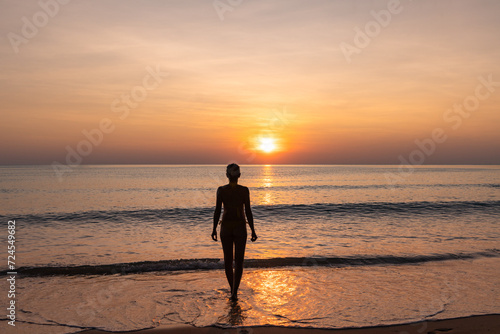 Peace and tranquility  silhouette of woman on paradisiacal beach admiring the sunset