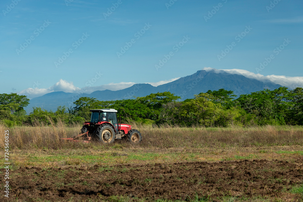 Obraz premium Blue sky over tractor plowing a field with Baru volcano in the background, Chiriqui, Panama, Central America - stock photo