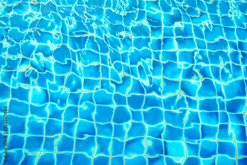 blue water wave pattern in swimming pool as the sun shines down during the day. Soft and selective focus. 
