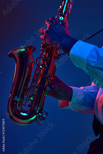 Major and Minor. Cropped photo of African-American man, holds Alto Sax and improvises jazz melodies in mixed neon lights. Concept of classical musical instrument, concerts and festivals. Ad photo