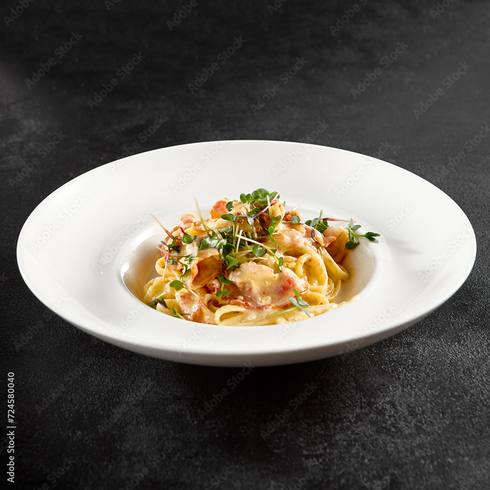 Classic carbonara pasta with a creamy sauce and garnished with fresh herbs, presented on a white plate Classic carbonara pasta with a creamy sauce and garnished with fresh herbs, presented on a white plate
