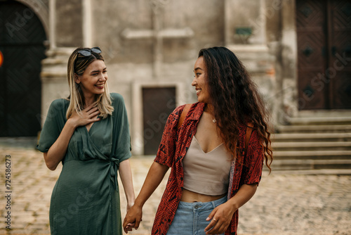 Wall Mural Young women holding hands and discovering new places and enjoying the urban vibe