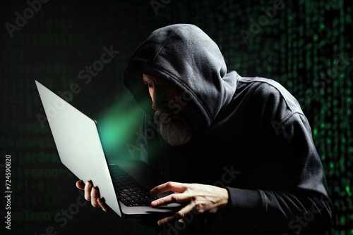 Pirate informatique masqué en train de pirater un ordinateur portable et qui demande une rançon devant un écran vert photo